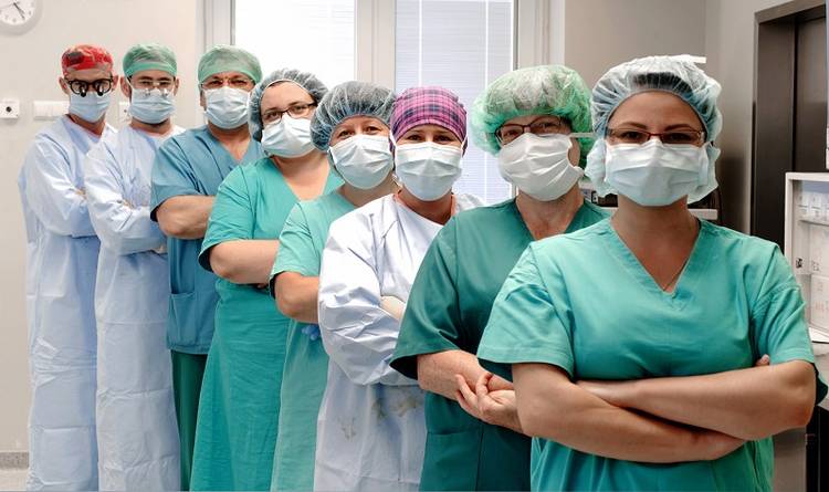 Zdjęcie grupy lekarzy ustawionych jeden obok drogiego w kitlach lekarskich