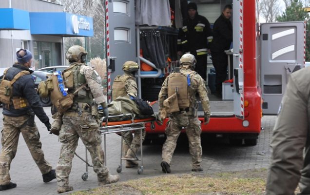 Żołnierze podczas ćwiczeń medycznych wnoszą do ambulansu poszkodowanego ułożonego na noszach.