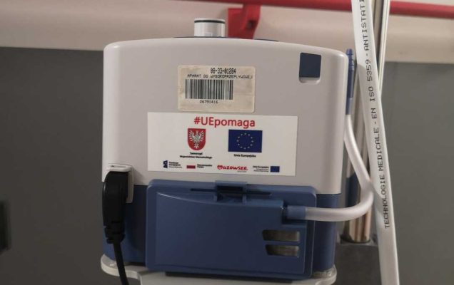 Ujęcie fragmentu aparatu do terapii tlenowej na korytarzu szpitalnym.