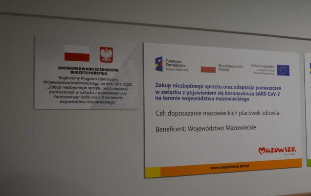 Dwie tablice z informacją o projekcie przyczepione obok siebie na ścianie korytarza szpitala.