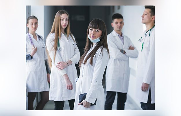 Grupa lekarzy w białych fartuchach na korytarzu szpitalnym