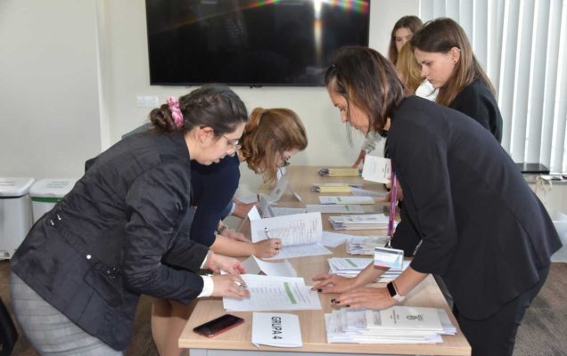 Grupa studentów podyplomowych wypełnia dokumenty przy stole.