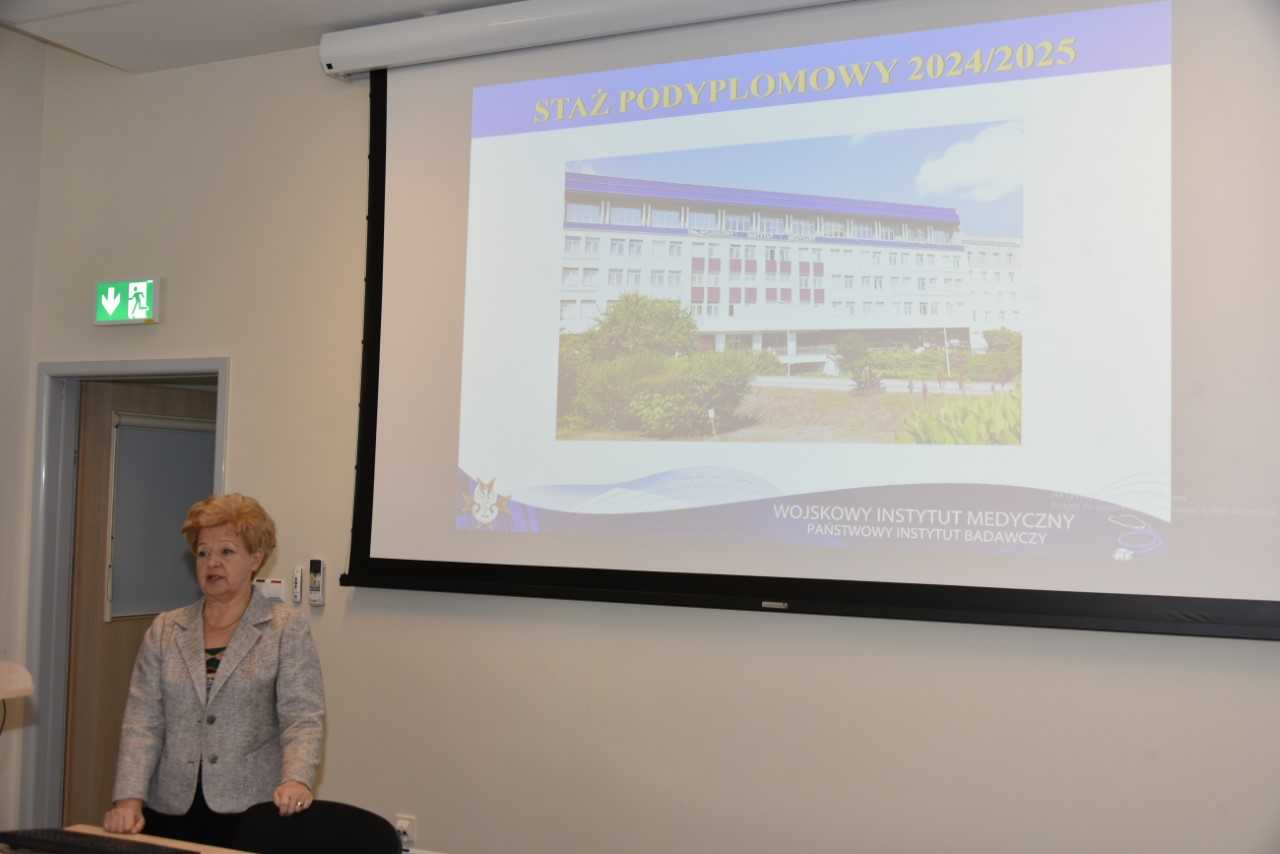 Dr hab. n. med. Jolanta Korsak podczas wykładu inauguracyjnego. Za jej plecami fragment wyświetlonej prezentacji z rzutnika.