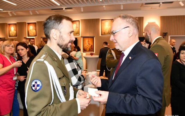 Spotkanie wigilijne w Wojskowym Instytucie Medycznym w Warszawie. Uczestnicy spotkania dzielą się opłatkiem.