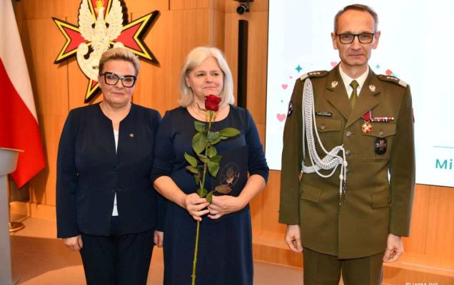 Dyrektor WIM Grzegorz Gielerak i Lidia Wojda, Beata Furtak trzymająca czerwoną różę pozują do zdjęcia.