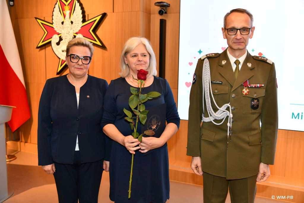 Dyrektor WIM Grzegorz Gielerak i Lidia Wojda, Beata Furtak trzymająca czerwoną różę pozują do zdjęcia.