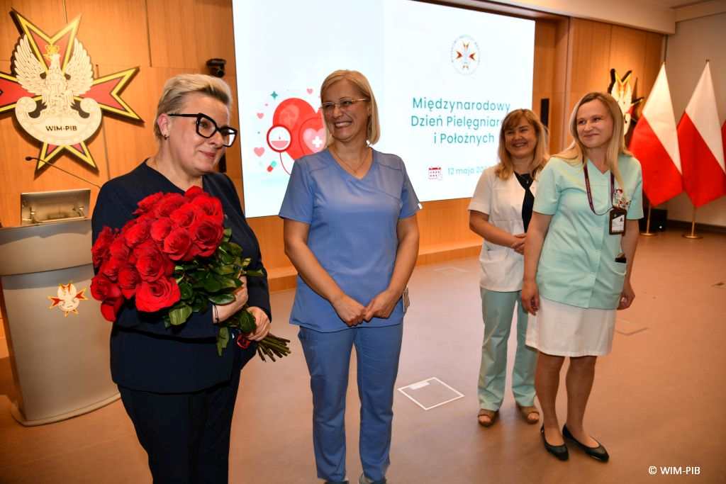 Lidia Wojda z bukietem róż i pielęgniarki.