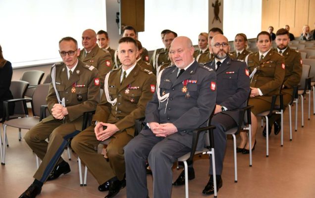 Siedzący goście na auli podczas uroczystości rozdania odznaczeń.