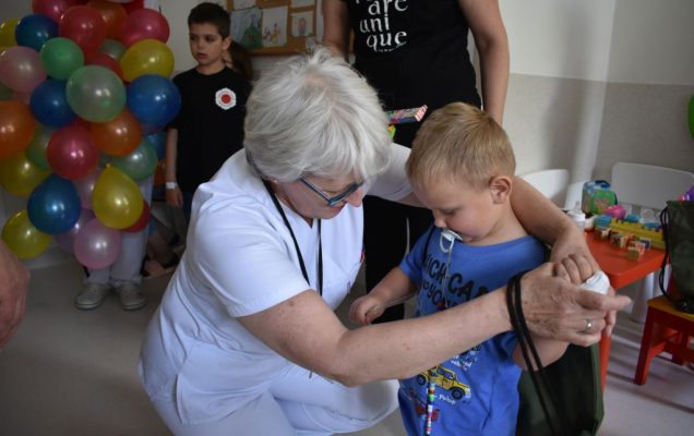 Pracownica WIM-PIB i kilkuletni chłopiec w trakcie wręczania prezentów.