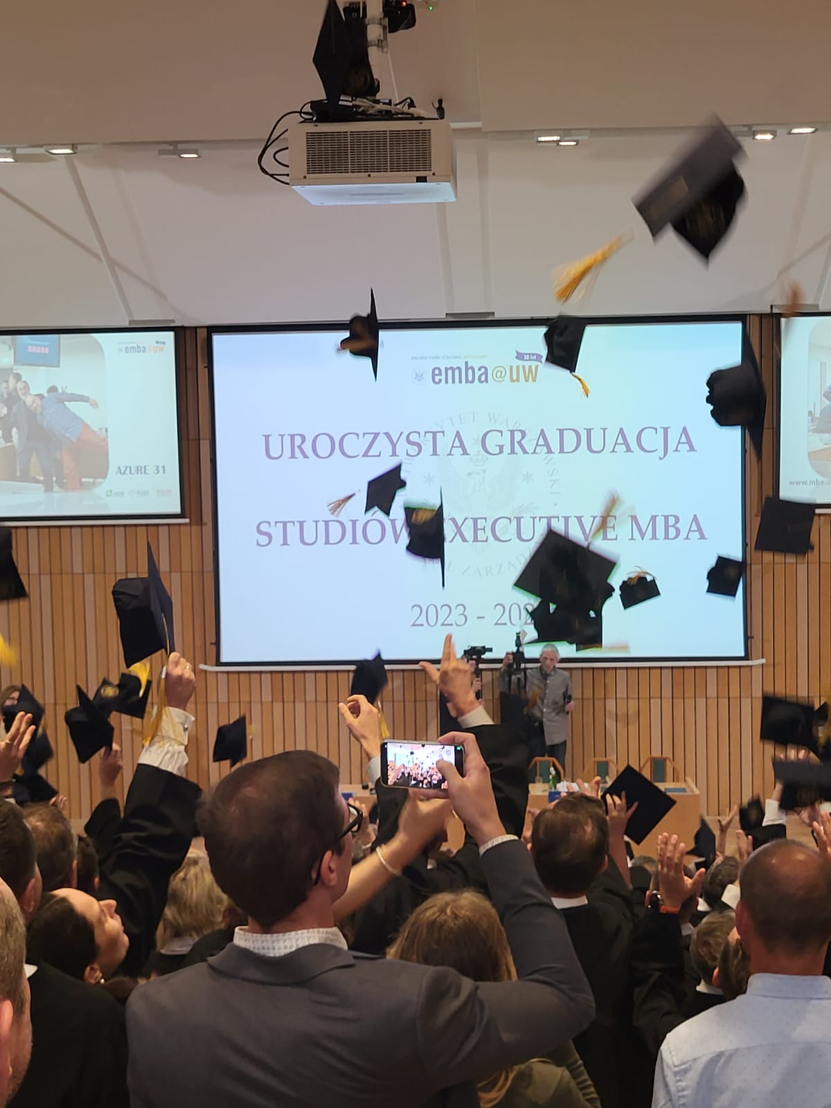 Studenci podrzucają czapki studenckie.