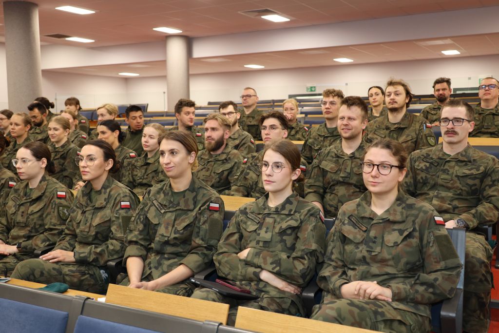 Lekarze w wojskowych mundurach siedzą na auli podczas konferencji.