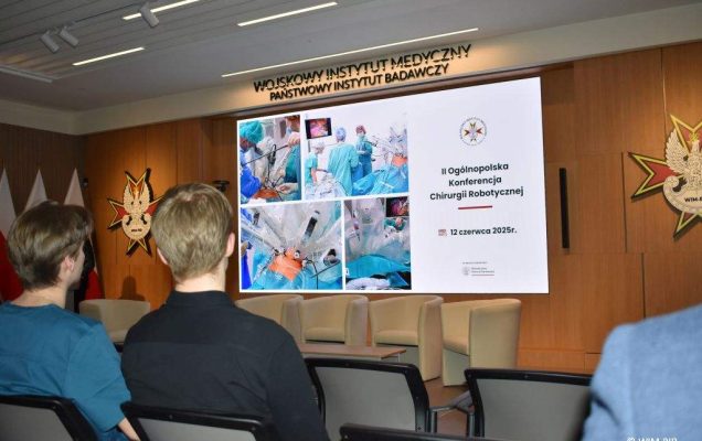 Słuchacze konferencji na sali, przed nimi na ekranie wyświetlony slaid z konferencji.
