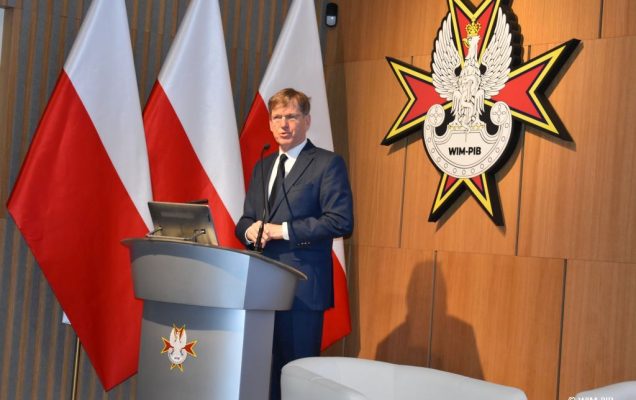 Prelegent przy mównicy podczas konferencji.