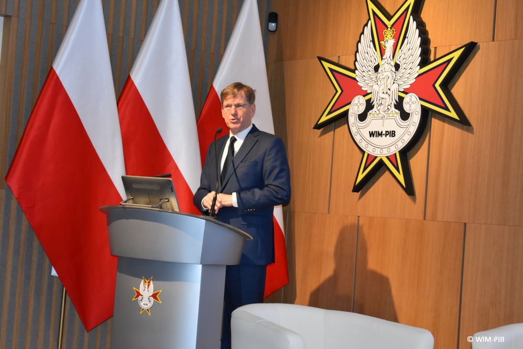 Prelegent przy mównicy podczas konferencji.
