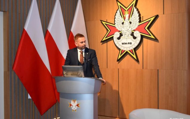 Prelegent przy mównicy podczas konferencji.
