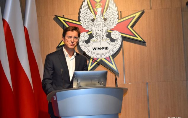 Prelegent konferencji przy mównicy.