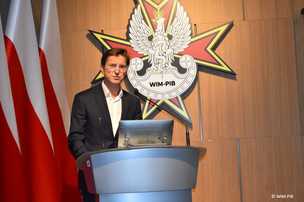 Prelegent konferencji przy mównicy.