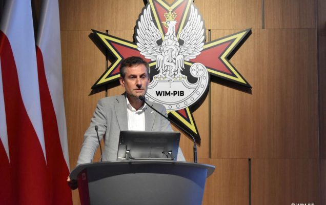 Prelegent konferencji przy mównicy.