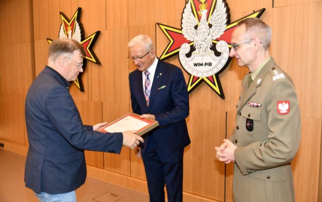 Wojciech Marczyński i Grzegorz Gielerak wręczają dyplom członkowi Rady.