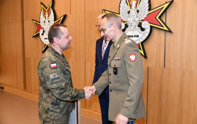 Wojciech Marczyński i Grzegorz Gielerak wręczają dyplom członkowi Rady ubranemu w mundur wojskowy.