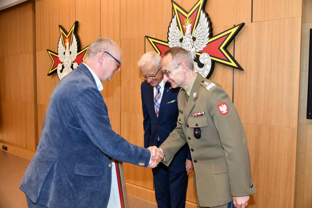 Wojciech Marczyński i Grzegorz Gielerak wręczają dyplom członkowi Rady.