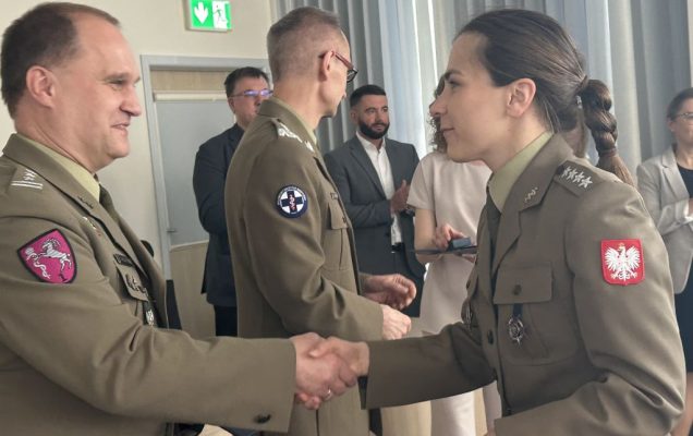 Studentka w mundurze wojskowym ściska rękę pracownikowi WIM-PIB ubranemu w wojskowy mundur.