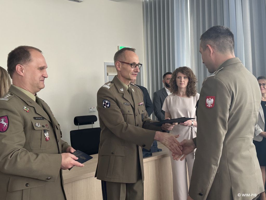 Dyrektor WIM-PIB wręcza dyplom studentowi ubranemu w wojskowy mundur.