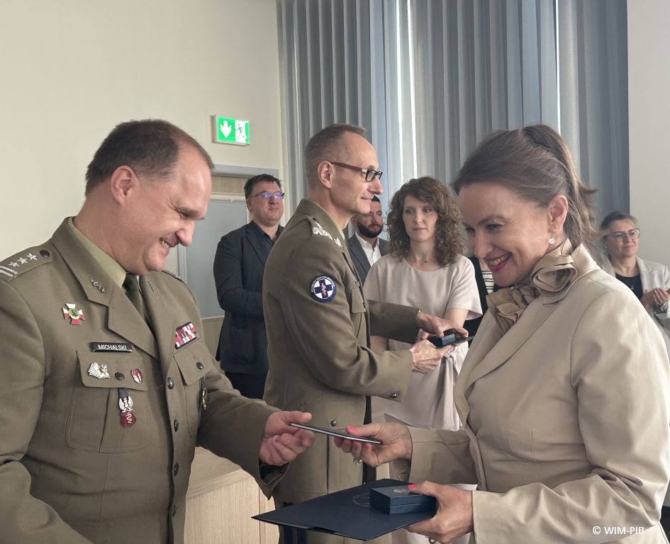 Studentka odbiera dyplom od pracownika WIM-PIB ubranego w wojskowy mundur.
