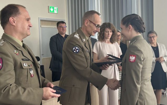 Dyrektor WIM-PIB Grzegorz Gierelak wręcza dyplom studentce ubranej w wojskowy mundur.
