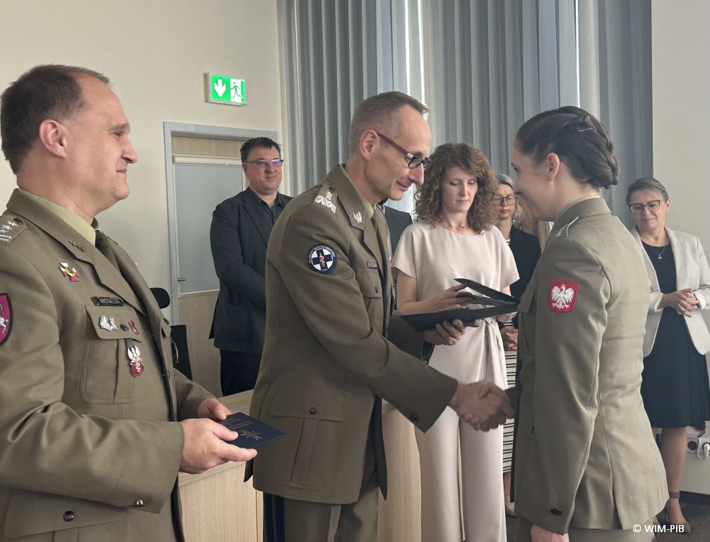 Dyrektor WIM-PIB Grzegorz Gierelak wręcza dyplom studentce ubranej w wojskowy mundur.