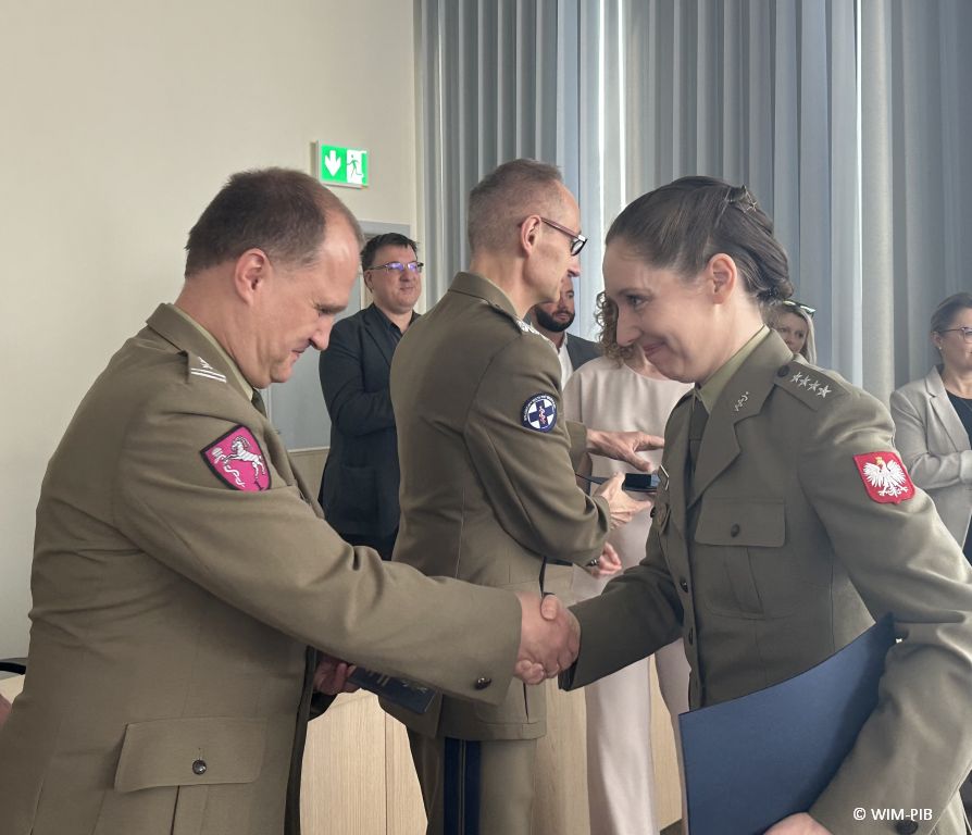 Pracownik WIM-PIB gratuluje studentce ubranej w wojskowy mundur.
