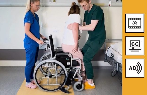 Sala szpitalna. Kobieta trzymająca za tył wózka inwalidzkiego na przeciw niej mężczyzna sadzający młoda kobietę na wózek. Po prawej stronie ikona wideo, ikona napisów i ikona audiodeskrypcji.