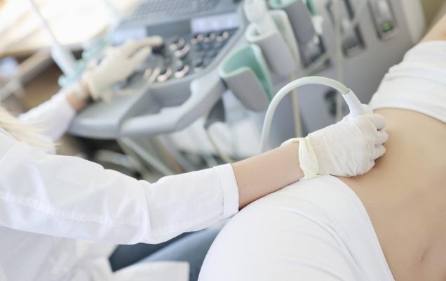 Gabinet zabiegowy. Ujęcei fragmentu sylwetki lekarza wykonującego badanie usg brzucha.