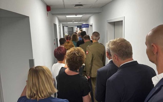 Pracownicy szpitala, goście i dziennikarze na korytarzu poradni.