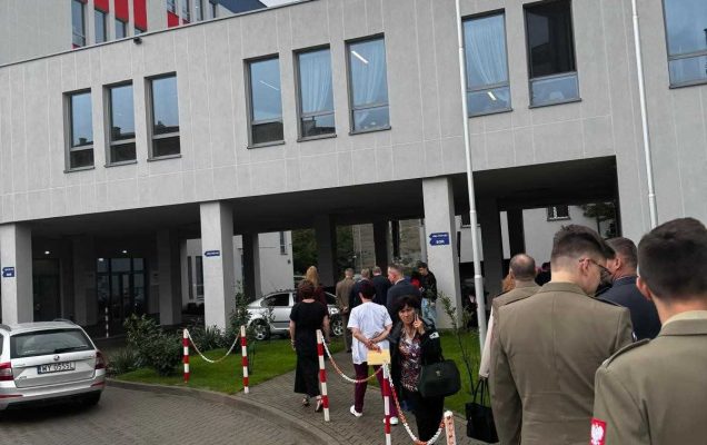 Goście cywilni i mundurowi idą w stronę budynku poradni.