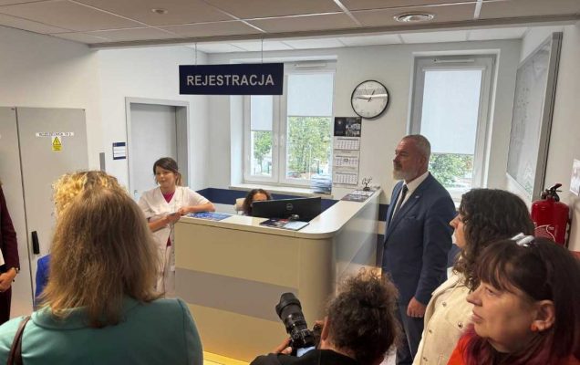 Rejestracja Poradni specjalistycznych w Legionowie. Goście i reporterzy przy kontuarze rejestracji.