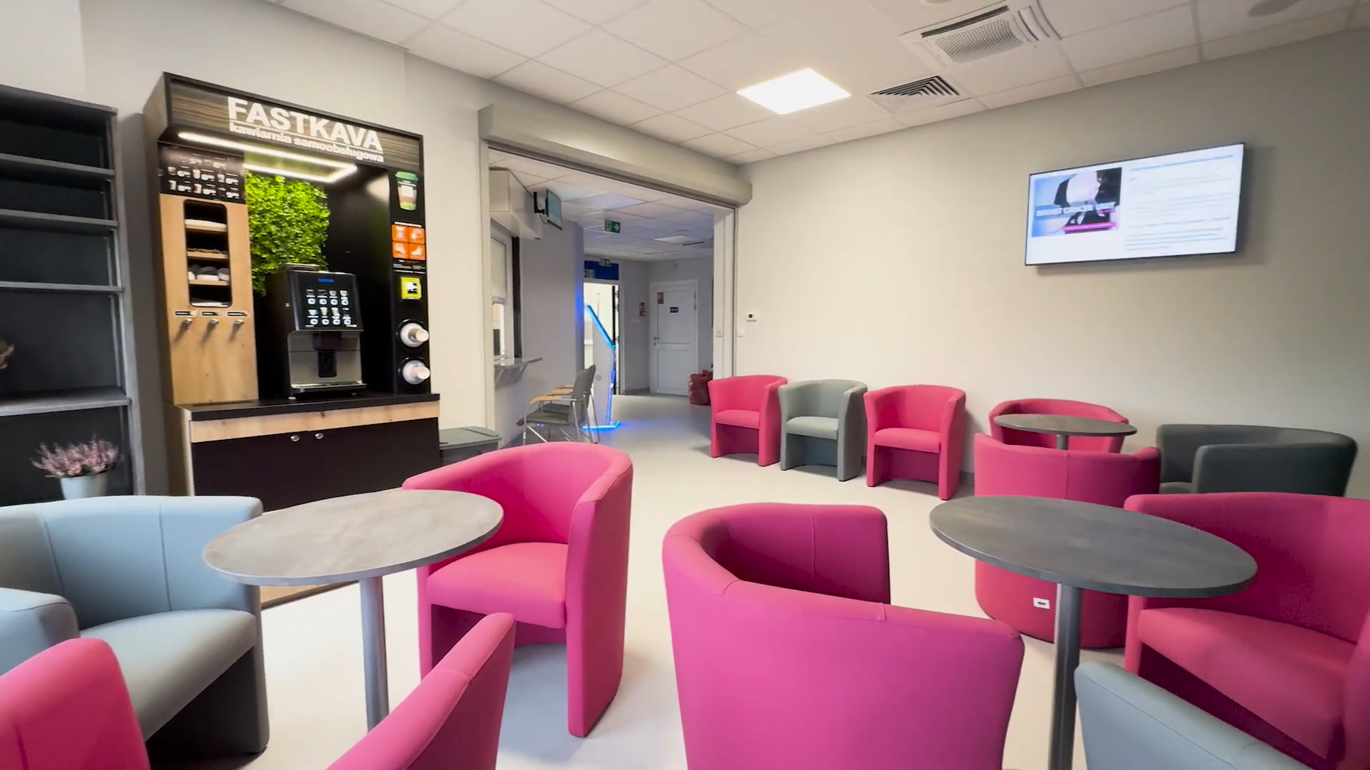 Poczekalnia Poradni Chorób Piersi. Okrągłe stoliki z różowymi fotelami.