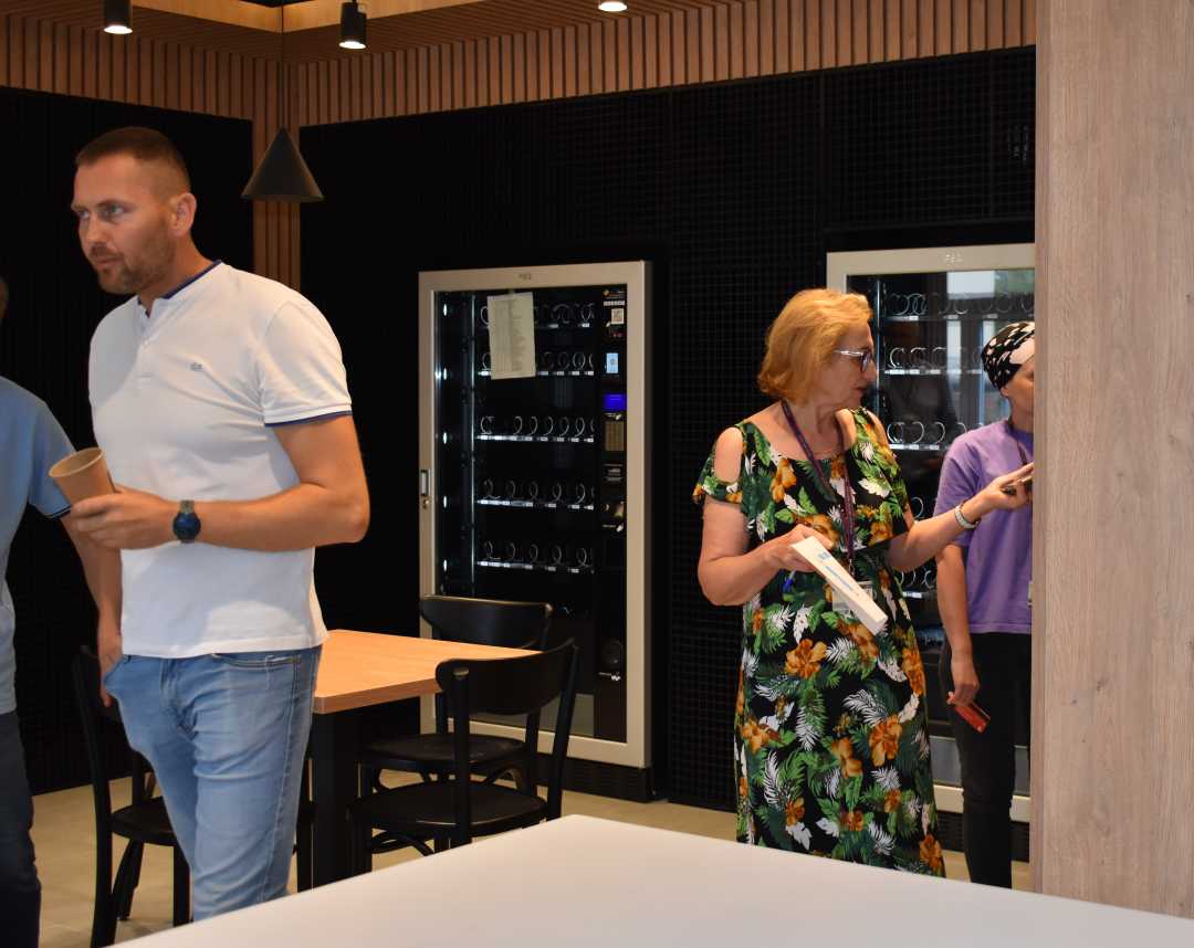 W pomieszczeniu przy automatach pracownicy i pacjenci korzystający z automatów z przekąskami.