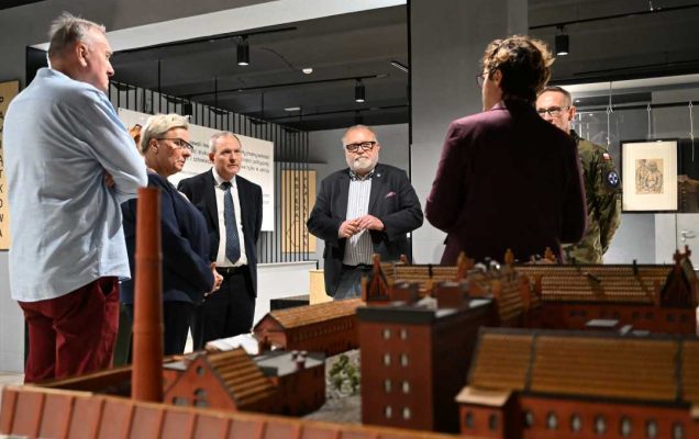 Pracownicy WIM w sali Muzeum Żołnierzy Wyklętych przy makiecie budynku.
