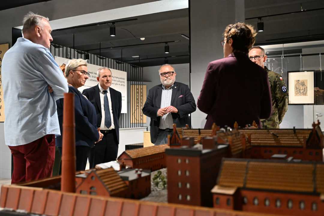 Pracownicy WIM w sali Muzeum Żołnierzy Wyklętych przy makiecie budynku.