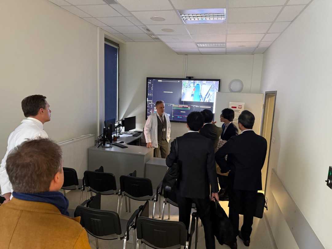 Delegacja z Japonii z lekarzami WIM na sali podczas szkolenia. W tyle sali na ścianie ekran z prezentacją.