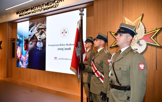 Aula WIM-PIB, trzech żołnierzy w mundurach galowych stoi na baczność z sztandarem Polski, obok nich wyświetlony napis Inauguracja Roku Akademickiego 2025/2026.
