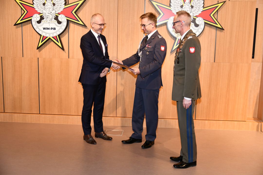 prof. Grzegorz Gielerak i prof. Paweł Krzesiński wręcza dyplom habilitacyjny Piotrowi Dąbrowieckiemu.