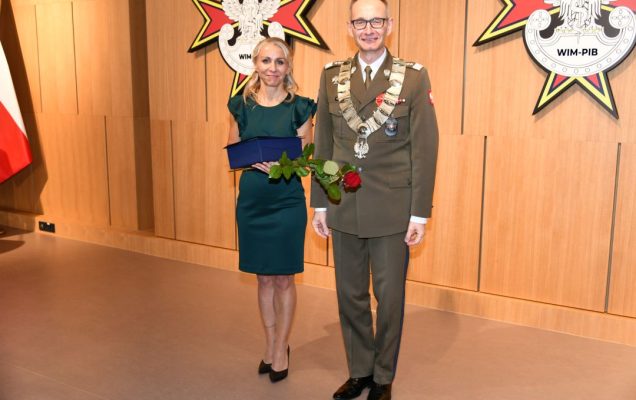 Małgorzata Złotkowska Główny specjalista ds. komunikacji wewnętrznej WIM z dyplomem i czerwona różą w rękach obok dyrektora WIM.