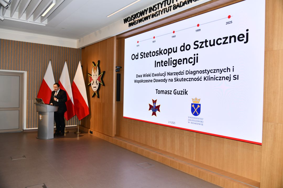 Aula WIM, przy mównicy Prof. dr hab. n. med. Tomasz Guzik, za nim wyświetlony na ekranie tytuł wykładu 
