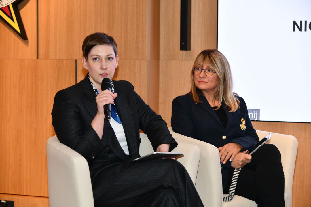 Dwie prelegentko podczas panelu, jedna z nich trzyma mikrofon w dłoni.