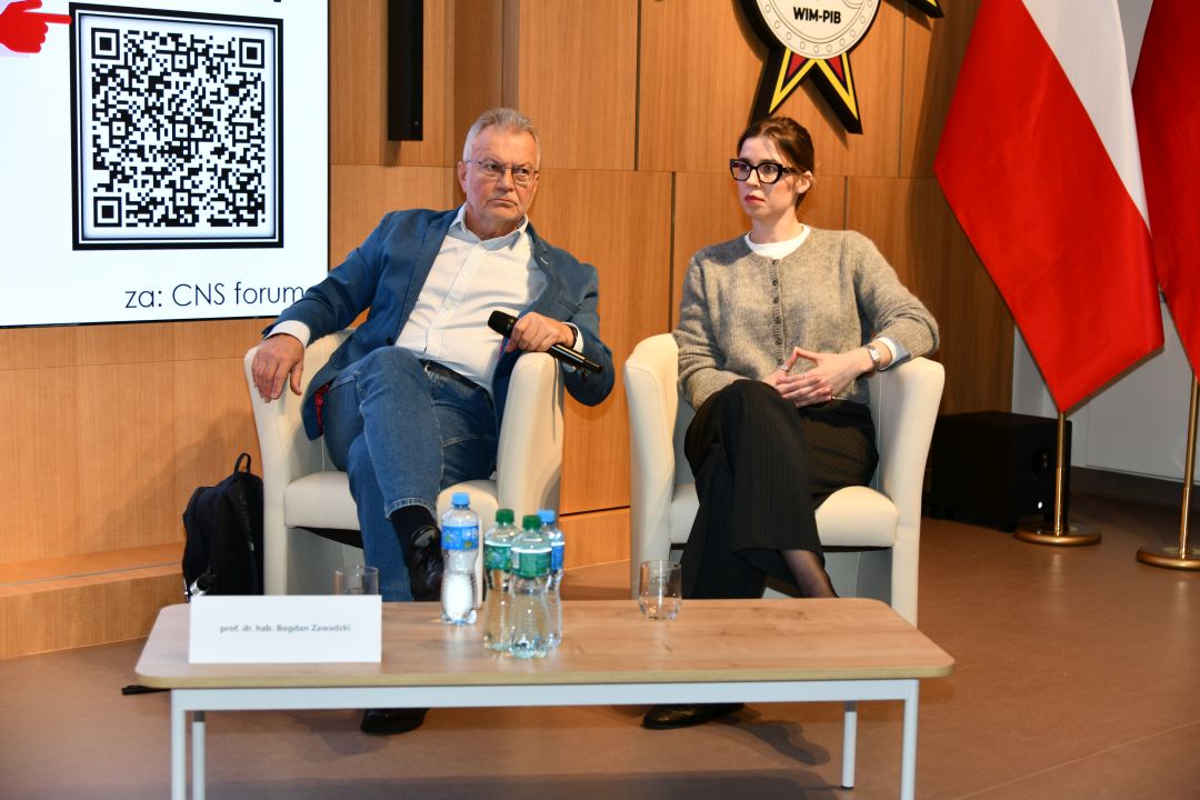 Prelegenci siedzący w fotelach podczas jednego z paneli.