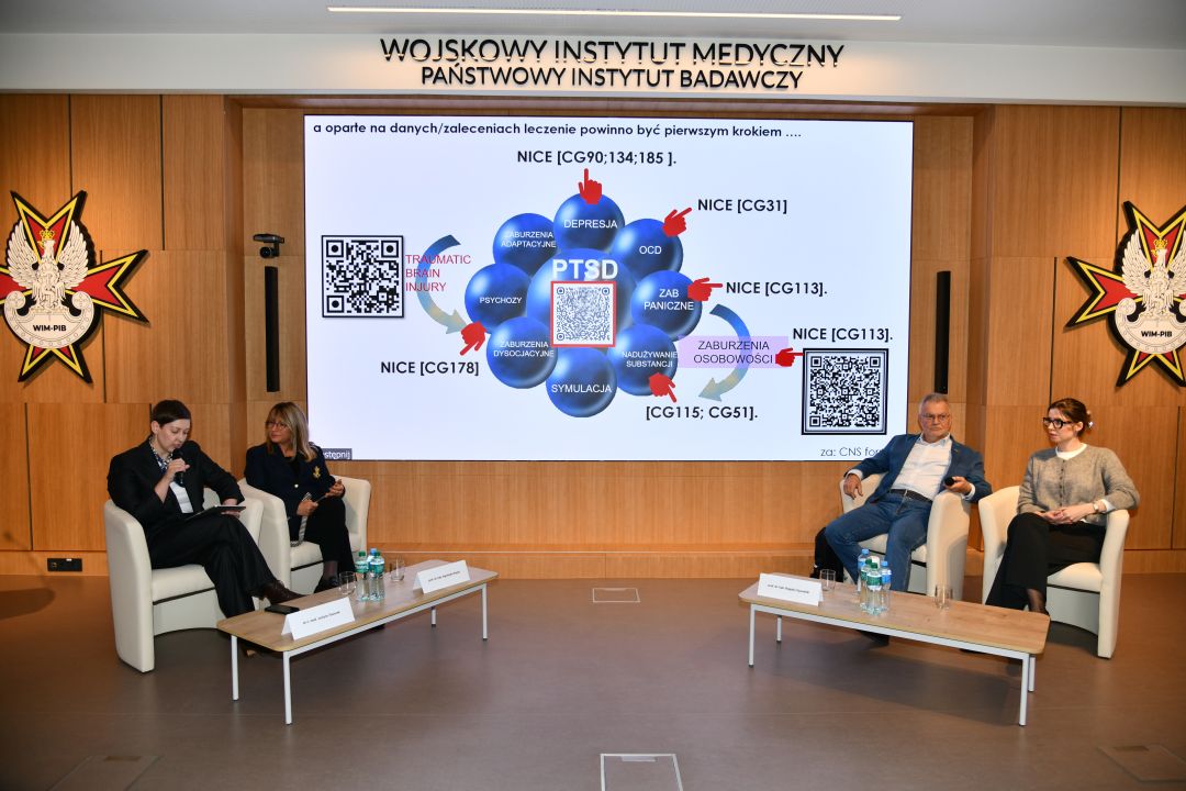 Czterech prelegentów siedzących na fotelach podczas jednego z paneli naukowych.