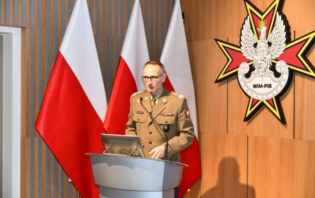 Dyrektor WIM-PIB ubrany w mundur wojskowy przy mównicy.