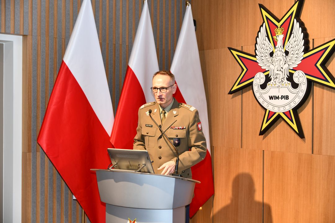 Dyrektor WIM-PIB ubrany w mundur wojskowy przy mównicy.